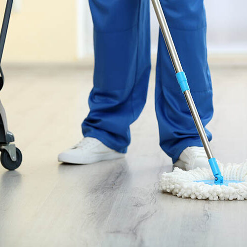 A cleaner with a mop cleaning the floor as part of facilities management